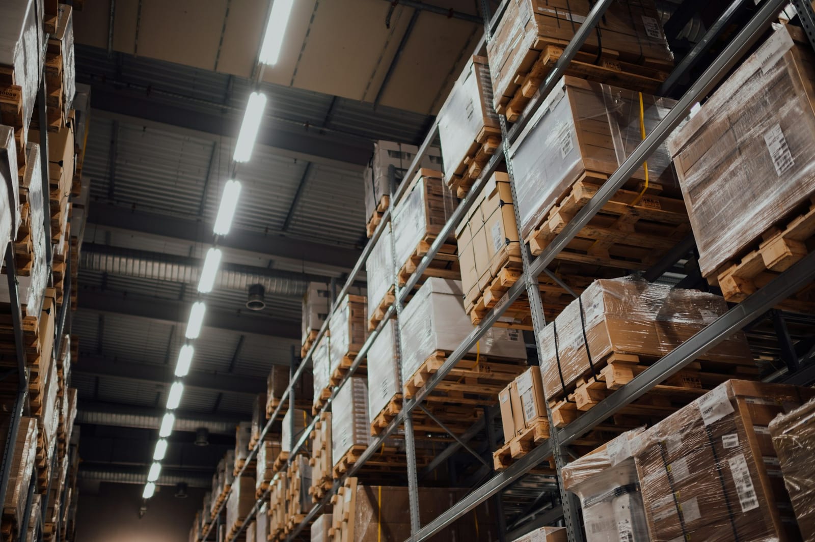 Cardboard shipping boxes neatly stacked on white metal racks inside a warehouse.