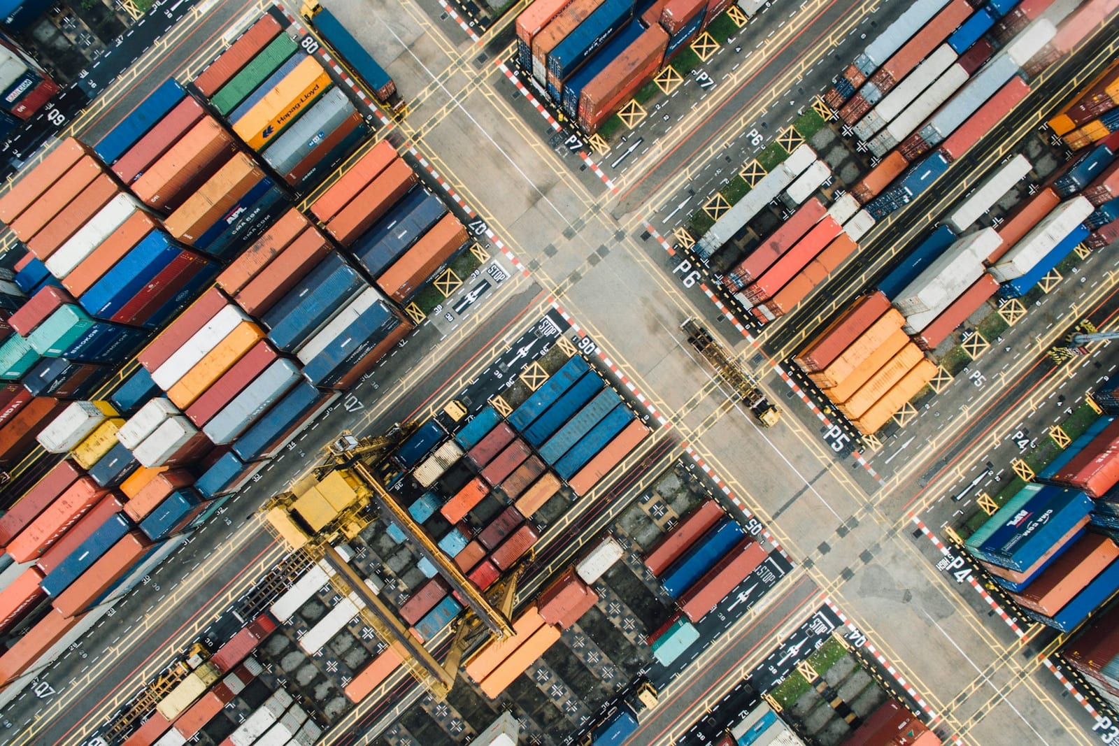 Aerial view of a shipping container yard stacked with multicoloured cargo containers.